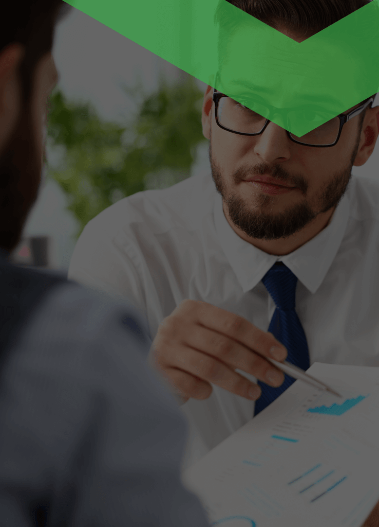 Ein Berater im weißen Hemd und mit Krawatte erklärt einem Kunden ein Dokument mit Diagrammen und Finanzdaten. Die Szene symbolisiert ein Beratungsgespräch über Kreditvoraussetzungen wie Bonität, Einkommen oder Sicherheiten.