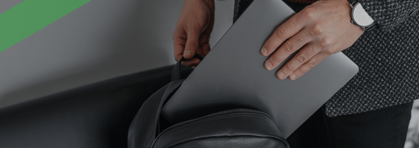 Eine Person steckt ein silbernes Laptop in einen schwarzen Rucksack. Die Szene symbolisiert einen kürzlich erfolgten Kauf, möglicherweise über einen Finanzkauf oder Ratenkredit finanziert.