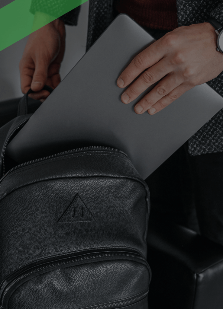 Eine Person steckt ein silbernes Laptop in einen schwarzen Rucksack. Die Szene symbolisiert einen kürzlich erfolgten Kauf, möglicherweise über einen Finanzkauf oder Ratenkredit finanziert.