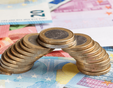 Eine Brücke aus gestapelten Euromünzen überspannt mehrere Euro-Geldscheine. Die Szene symbolisiert finanzielle Stabilität und langfristige Finanzierungslösungen, wie sie bei langfristigen Krediten zum Tragen kommen.