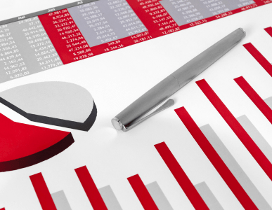 Ein Kugelschreiber liegt auf einem Finanzdokument mit roten und grauen Balken- und Kreisdiagrammen sowie einer Tabelle. Die Szene symbolisiert die Analyse betriebswirtschaftlicher Kennzahlen, insbesondere des Verschuldungsgrads eines Unternehmens.