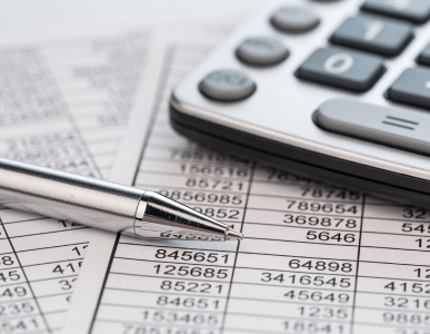 Ein Kugelschreiber liegt auf einem Zahlenformular, daneben ein Taschenrechner. Die Szene symbolisiert die Berechnung oder Verwaltung von Kreditverpflichtungen, insbesondere im Kontext eines Wechselkredits, bei dem ein Kredit durch einen Wechsel abgesichert ist.