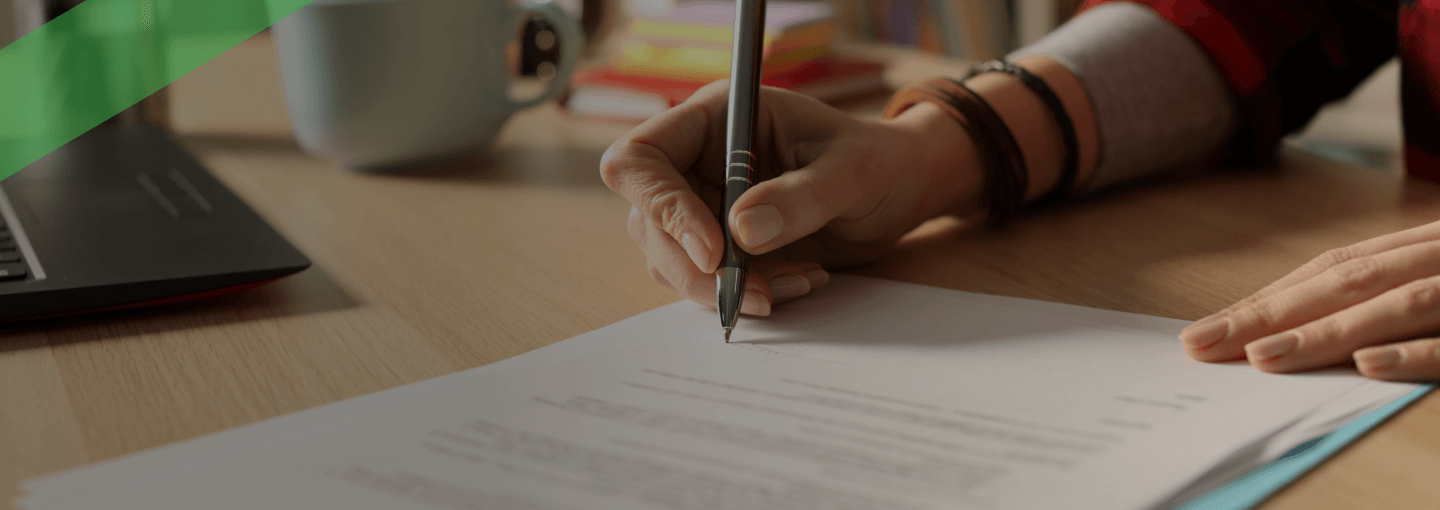 Eine Person unterschreibt ein offizielles Dokument auf einem Schreibtisch, daneben liegen eine Tasse und Schreibutensilien. Die Szene symbolisiert die Unterzeichnung einer Bürgschaft, bei der jemand für die Verpflichtungen einer dritten Person haftet.