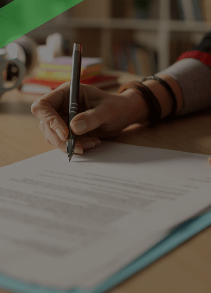 Eine Person unterschreibt ein offizielles Dokument auf einem Schreibtisch, daneben liegen eine Tasse und Schreibutensilien. Die Szene symbolisiert die Unterzeichnung einer Bürgschaft, bei der jemand für die Verpflichtungen einer dritten Person haftet.