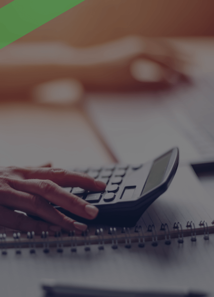 Eine Person tippt auf einem Taschenrechner, während im Hintergrund ein Laptop geöffnet ist. Auf dem Tisch liegen ein Notizbuch, ein Smartphone, eine Brille und Diagramme. Die Szene symbolisiert die Berechnung und Planung variabler Kreditkonditionen, etwa bei einem Cap-Darlehen mit Zinsobergrenze.