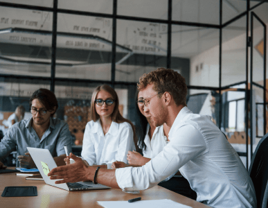 Eine Gruppe junger Menschen in Businesskleidung sitzt gemeinsam an einem Konferenztisch und diskutiert vor einem Laptop. Die Szene symbolisiert Entscheidungs- und Handlungsfähigkeit im geschäftlichen Kontext, etwa im Zusammenhang mit der rechtlichen Geschäftsfähigkeit.
