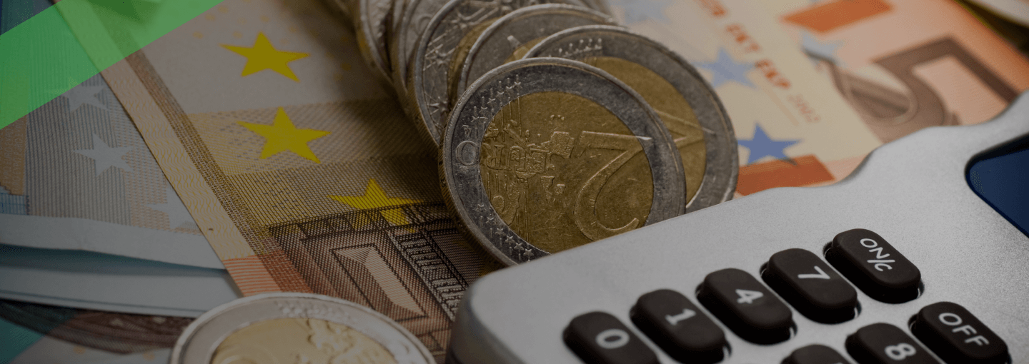 Mehrere gestapelte Euromünzen liegen auf Euro-Banknoten neben einem Taschenrechner. Die Szene symbolisiert finanzielle Kalkulationen im Zusammenhang mit kurzfristigen Krediten oder Liquiditätsengpässen.
