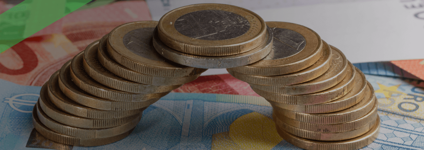 Eine Brücke aus gestapelten Euromünzen überspannt mehrere Euro-Geldscheine. Die Szene symbolisiert finanzielle Stabilität und langfristige Finanzierungslösungen, wie sie bei langfristigen Krediten zum Tragen kommen.