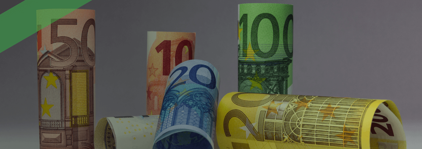 Verschiedenfarbige Euro-Geldscheine sind zu Rollen geformt und stehen oder liegen aufrecht nebeneinander. Die Szene symbolisiert den Roll-over-Kredit, bei dem ein Kreditbetrag regelmäßig verlängert und zu variablen Konditionen neu verzinst wird.