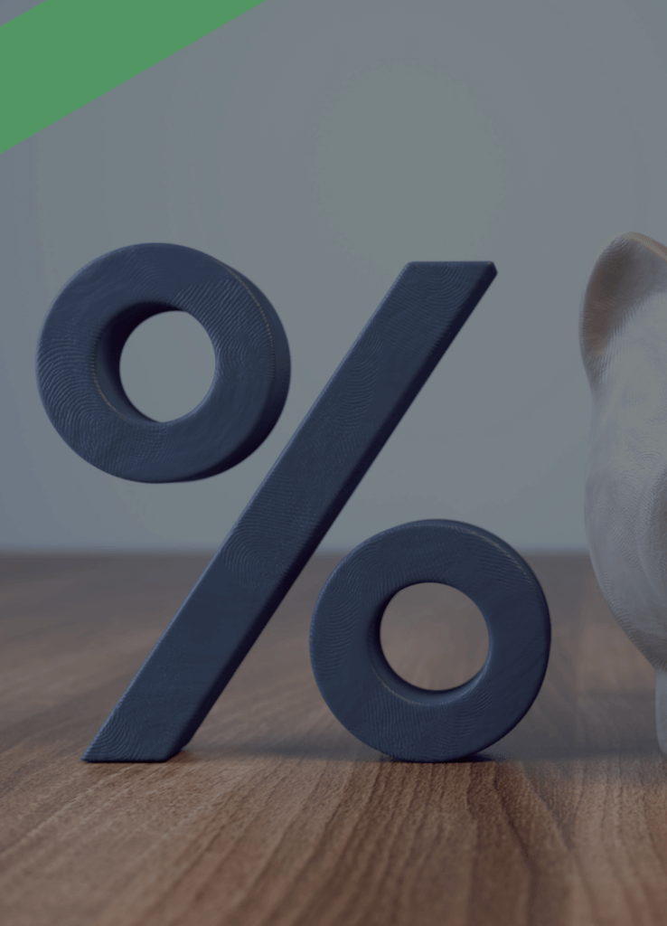 Ein weißes Sparschwein steht auf einem Holztisch neben einem großen Prozentzeichen. Die Szene symbolisiert ein variables Darlehen, bei dem sich die Zinshöhe während der Laufzeit ändern kann.