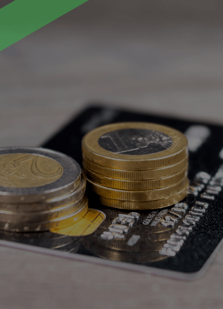 Gestapelte Euro-Münzen liegen auf einer Kreditkarte, die auf einem Holztisch platziert ist. Die Szene symbolisiert finanzielle Transaktionen, Kreditverfügbarkeit oder flexible Zahlungsmöglichkeiten wie bei einem Abruf- oder Rahmenkredit.