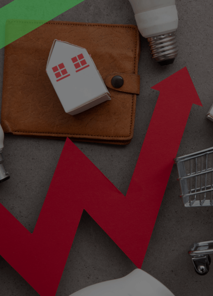 Eine rote Zickzacklinie mit Pfeil nach oben verläuft zwischen Symbolen für Konsum und Wohnen: Miniaturhäuser, ein Einkaufswagen, Glühbirnen und eine Geldbörse. Die Szene symbolisiert Inflation und den Anstieg der Lebenshaltungskosten.