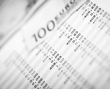 Nahaufnahme eines Kontoauszugs oder Abrechnungsdokuments, auf dem verschiedene Buchungen und Beträge zu sehen sind. Im Hintergrund ist ein 100-Euro-Schein erkennbar. Die Szene symbolisiert regelmäßige Zahlungsverpflichtungen, etwa die monatliche Kreditrate.