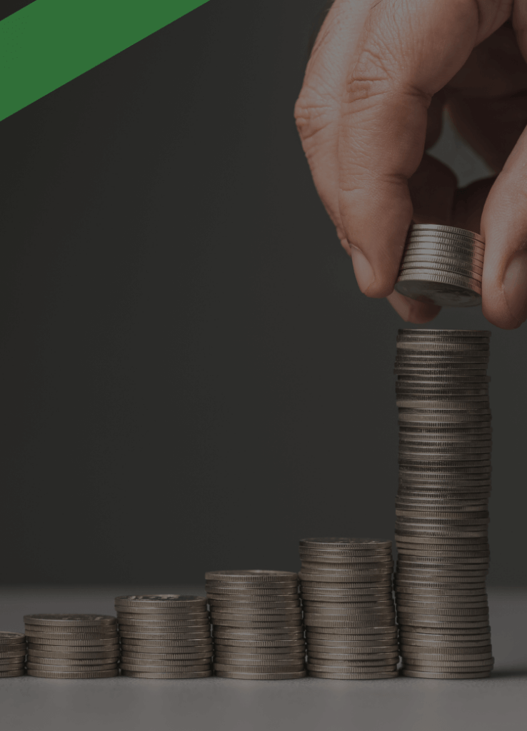 Eine Hand stapelt Münzen auf den höchsten einer Reihe von aufsteigend angeordneten Münzstapeln. Die Szene symbolisiert das Prinzip des Zinseszinses, bei dem sich Zinsen über die Zeit hinweg auf bereits entstandene Zinsen summieren und so das Vermögen wachsen lassen.